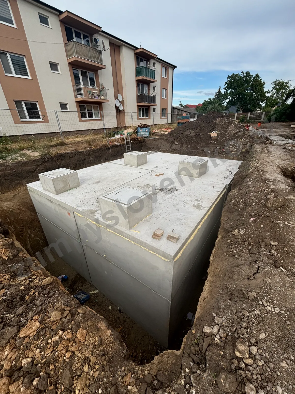 Zostava betónových nádrží s krycími doskami a hranatými komínmi vo výkope